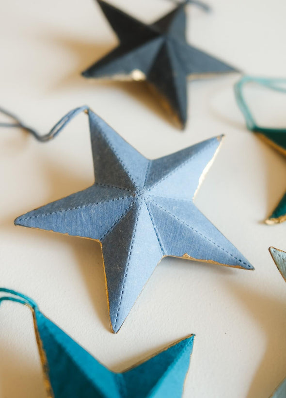 Blue star-shaped decorations on a string against a neutral background