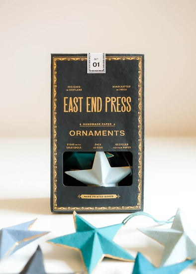 Box of East End Press ornaments with star-shaped paper decorations on a light background