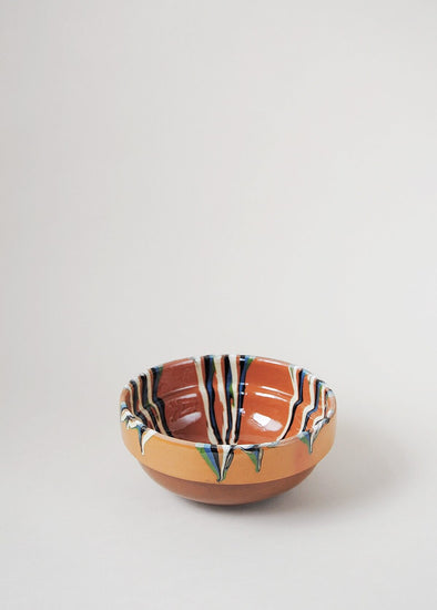 Ceramic bowl decorated in traditional Romanian pattern. Terracotta base with a striped design in cream, green and blue.