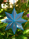 Blue and gold star-shaped ornament on a Christmas tree