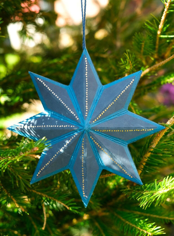 Blue and gold star-shaped ornament on a Christmas tree