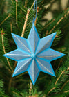Blue star-shaped ornament hanging on a Christmas tree