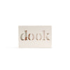 A rectangular soap encased in its cardboard packaging. The packaging has the brand name 'dook' cut out across the front.