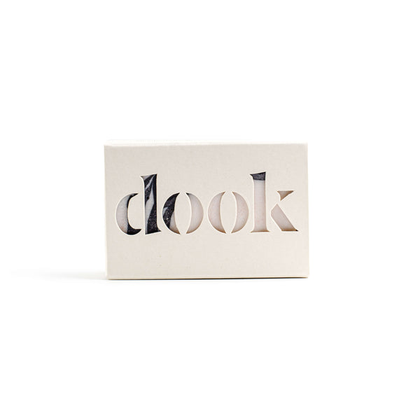 A rectangular soap encased in its cardboard packaging. The packaging has the brand name 'dook' cut out across the front.