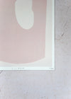 Close up of a corner of a print by Laurie Maun. Depicting a large abstract form in pale pink on a cream background, with a white border. Numbered by the artist in the corner.