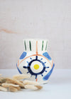 Ceramic vase with a white base and hand painted pattern of bold brush strokes in the colours green, orange, blue and yellow. Height fifteen centimetres, width twelve centimetres.