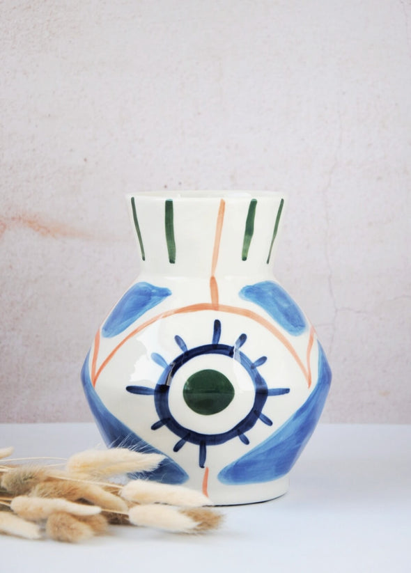 Ceramic vase with a white base and hand painted pattern of bold brush strokes in the colours green, orange and blue. Height nineteen point five centimetres, width sixteen centimetres
