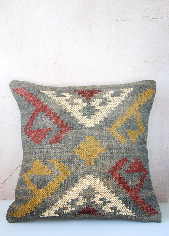 Blue cushion with a yellow, red and cream pattern. Made from wool and jute with a one hundred percent cotton back with zip closure. Measures forty five centimetres by forty five centimetres.