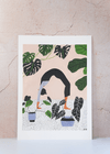 Art print by Rachel Victoria Hillis. Depicting a woman doing a yoga pose surrounded by green leaves and plants, on a pale pink background and white floor with black polka dots.
