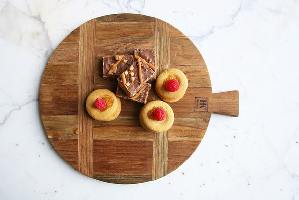 Selection of small pastries resting on a round wooden bread board.