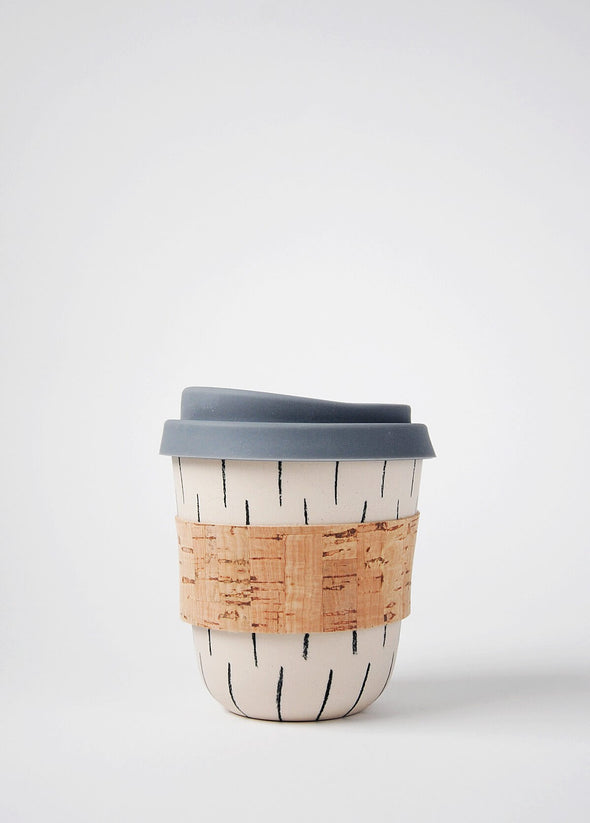 Reusable ceramic coffee cup with a cream base and hand decorated with a dark grey vertical dash pattern. It has a cork sleeve around the middle and a grey blue silicone lid. The cup is 10cm high (without lid), and 8.5cm wide (at top)
