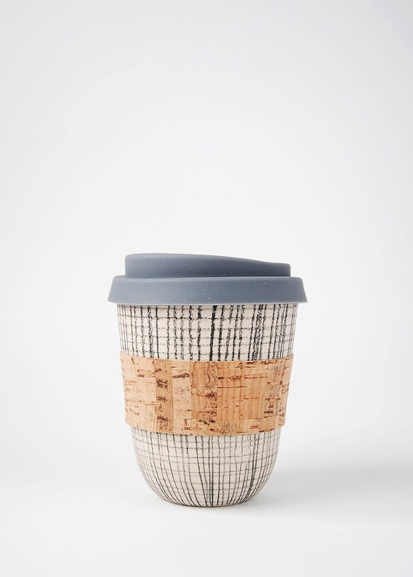Reusable ceramic coffee cup with a cream base and hand decorated with a dark grey small grid pattern. It has a cork sleeve around the middle and a grey blue silicone lid. The cup is 10.5cm high (without lid), and 9cm wide (at top)