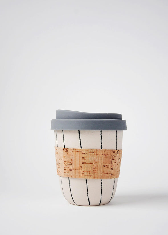 Reusable ceramic coffee cup with a cream base and hand decorated with dark grey vertical stripes. It has a cork sleeve around the middle and a grey blue silicone lid. The cup is 10cm high (without lid), and 8.5cm wide (at top)