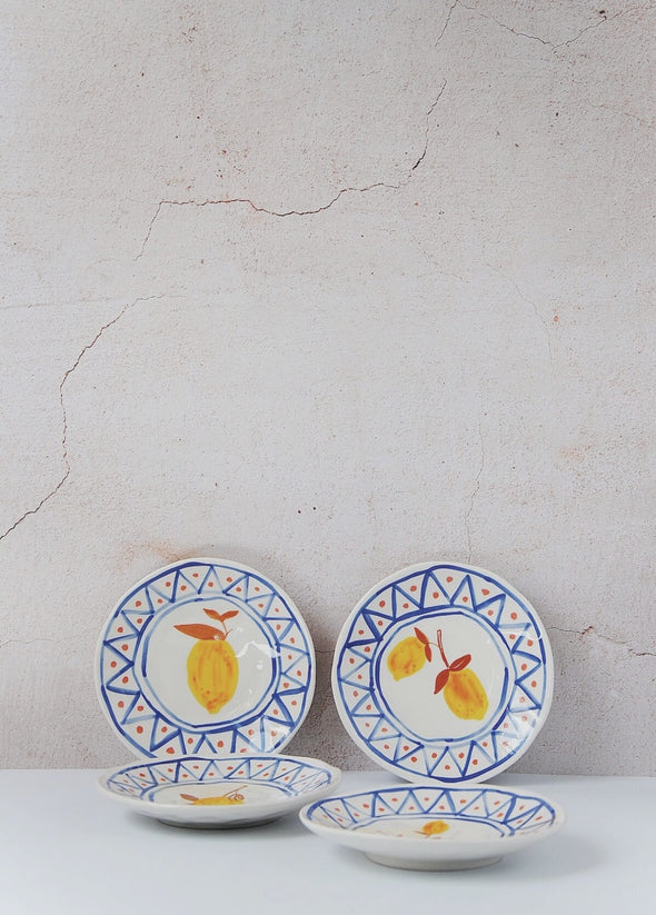 Set of four plates. Each has a white base and hand painted patterns and lemons in yellow, blue and brown. Height two point five centimetres, width sixteen centimetres.
