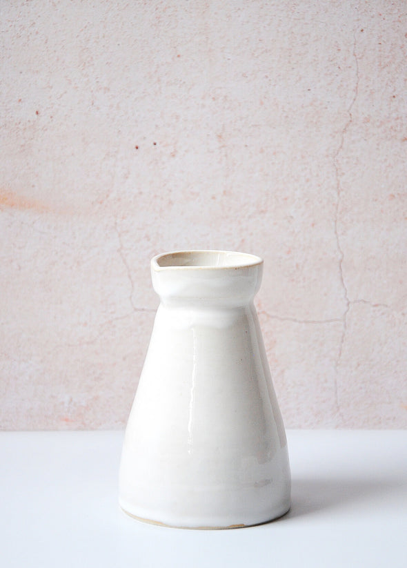 Small pourer handmade by Dor and Tan using local Cornish clay. It has a white glaze and is thirteen point five centimetres tall and six centimetres wide at the top opening. It has a capacity of six hundred and fifty millilitres.