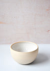 Bowl handmade by Dor and Tan using local Cornish clay. It has a white glaze inside and a rustic, natural exterior finish. Each bowl is seven point five centimetres high and fourteen point five centimetres wide.
