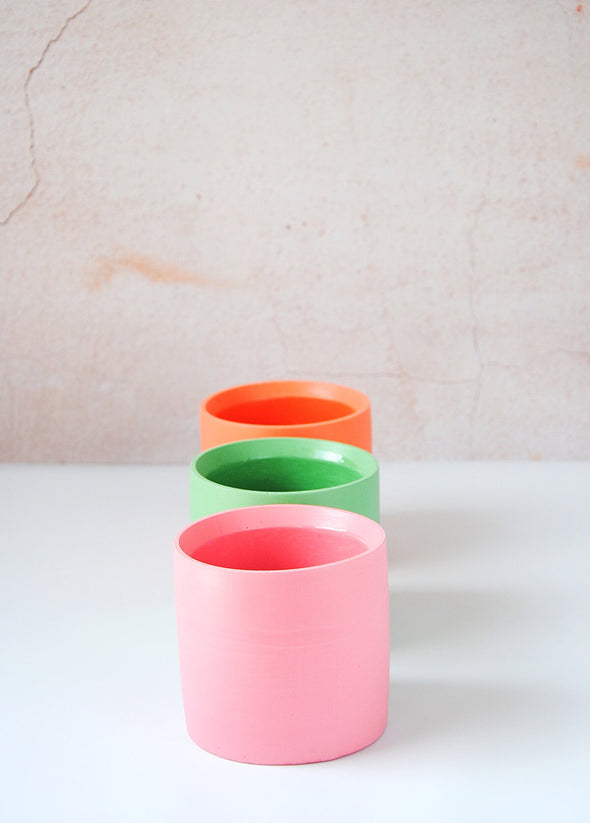 Collection of three planters all handmade by Salt Studios. One pink, one green and one orange.