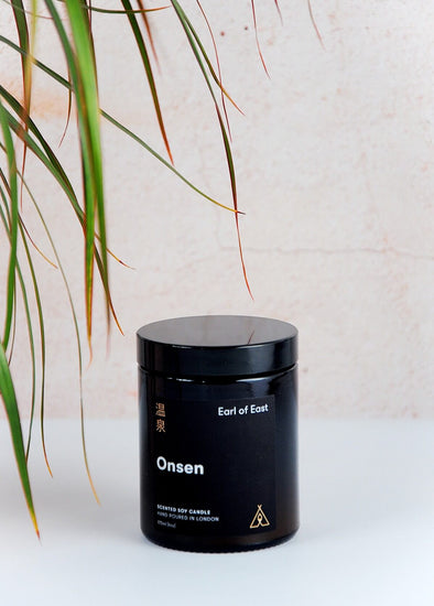 Scented candle in a brown apothecary inspired jar, made by Earl of East London using only natural soy wax. The label shows the name as being Onsen. The jar has a capacity of one hundred and seventy millilitres and is eight centimetres tall and six point five centimetres wide.