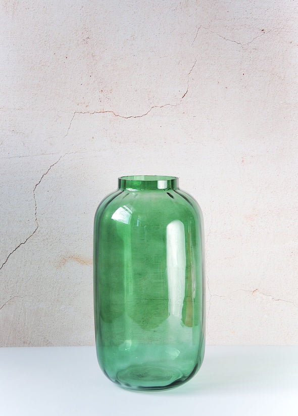 Clear glass vase in a jewel green colour. A classic shape with clean lines and a subtle ridged design, it is beautiful for displaying flowers and foliage. Height thirty-two centimetres, width sixteen centimetres.