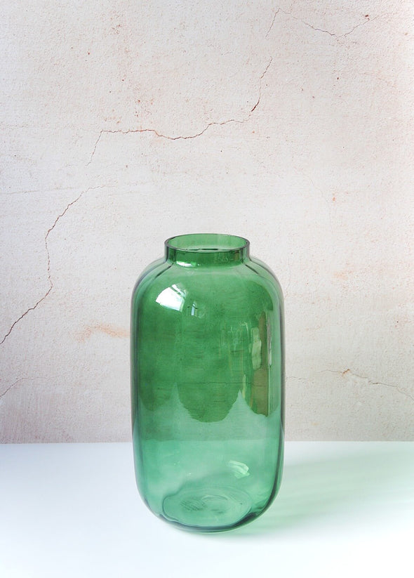 Clear glass vase in a jewel green colour. A classic shape with clean lines and a subtle ridged design, it is beautiful for displaying flowers and foliage. Height thirty-two centimetres, width sixteen centimetres.