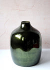 Deep green vase made from glass. Large body with a small opening to display one or a few stems, or can be used as a striking standalone piece. Twenty-nine point five centimetres tall and twenty-four point five centimetres wide. The neck is five point five centimetres wide.