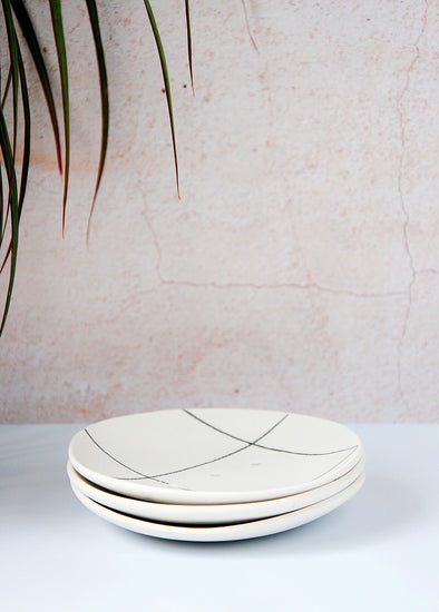 Three white circular porcelain soap dishes, featuring a large dark grey grid pattern, stacked on top of each other. Each dish is approximately 14cm across.