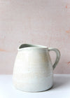 Jug with handle, ivory colour, made from porcelain with a rustic finish. Fifteen centimetres tall.