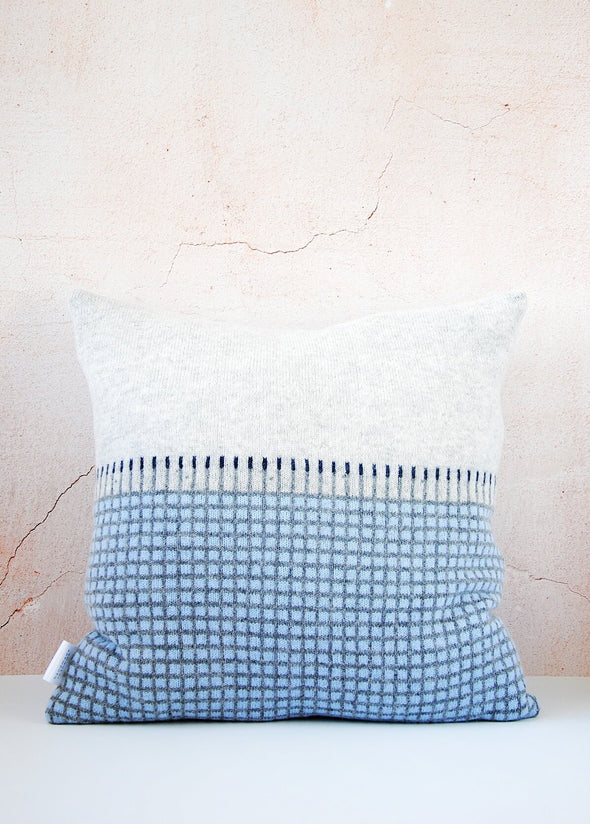 Light grey knitted lambswool cushion with a darker grey and light blue checked pattern on the bottom half. Height forty five centimetres, width forty five centimetres.