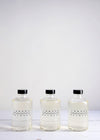 Three glass bottles of foam bath by London Bathers lined up in a row. Each glass bottle has a black plastic cap.