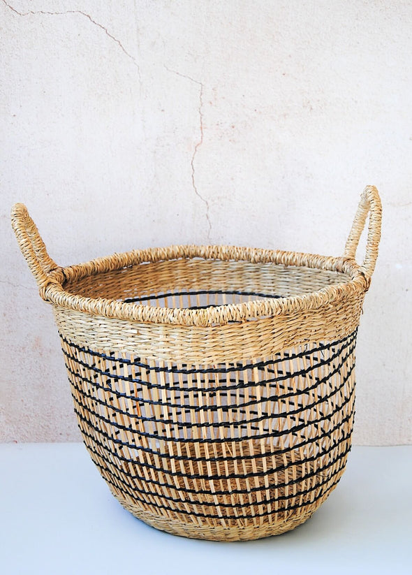 Small open weave seagrass basket in natural and black with handles. Height twenty six centimetres, width thirty one centimetres.