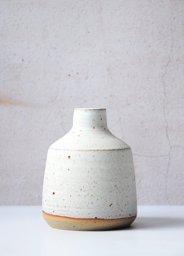 Stoneware bottle vase, handmade by JG Pottery. Featuring a white glaze, perfect for displaying a single stem. Thirteen centimetres tall and eleven centimetres wide at its base.