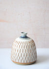 Stoneware dome shaped bud vase covered with fine vertical decorative carving, handmade by JG Pottery. Featuring a white glaze on its body with a blue over dip on its neck. Perfect for displaying a single stem. Fourteen centimetres tall and eleven centimetres wide at its base.