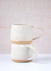 Two stoneware mugs stacked on top of each other. Handmade by JG Pottery with a white glaze and rustic finish.