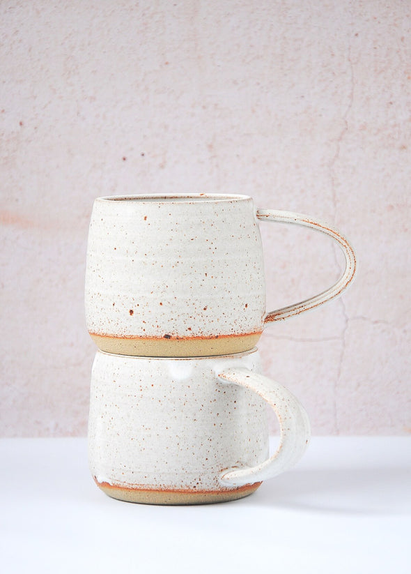 Two stoneware mugs stacked on top of each other. Handmade by JG Pottery with a white glaze and rustic finish.