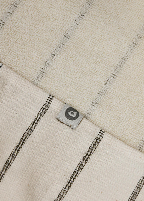 Close up of a towel in a cream and grey stripe design, showing both the smooth top and the flannel underside of the towel.