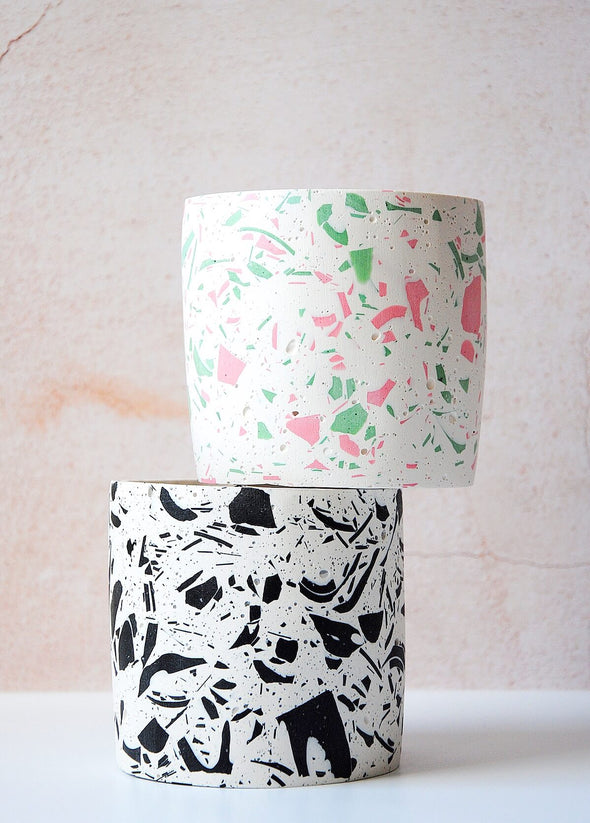 Two terrazzo planters stacked on top of each other, both are handmade by Salt Studios. One has a white base with pink and green terrazzo detail, the other has a white base with black terrazzo detail.