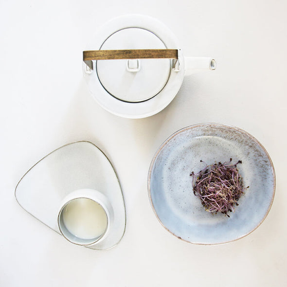 A bowl, cup and saucer and a white ceramic teapot seen from above. All are made from white and light blue coloured ceramic.