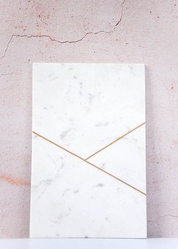 White marble board featuring a gold design of two straight lines. Each board is twenty centimetres by thirty centimetres.