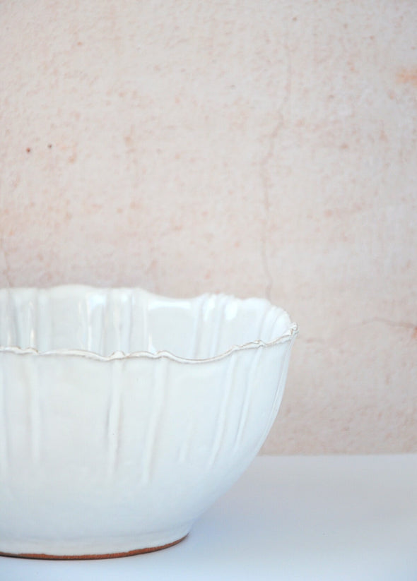 Close up of a bowl with fluted edges in a white glaze. Made from terracotta. Nine centimetres high and twenty centimetres wide.