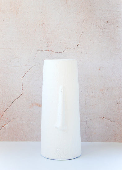 A playful yet simple nod to the abstract faces decorative style. This tall white vase is made from terracotta and features a sculpted long nose down the front. Height forty centimetres, Width seventeen centimetres.